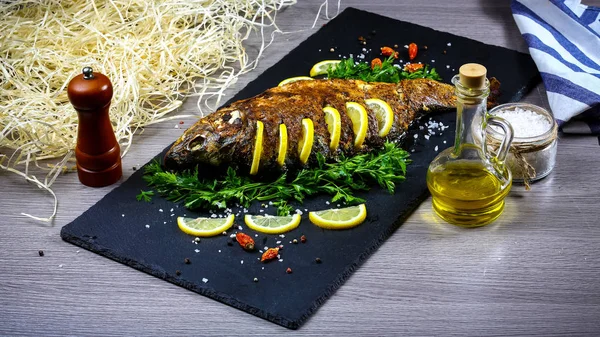 Grilled river fish on a plate with lemon and baked vegetables and parsley. Food recipe photo, copy text.