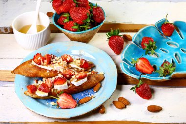 İtalyan bruschetta, çilekli, fındıklı ve peynirli camembert. Mutfak masasının beyaz arka planında yemek malzemeleri var. Düz yat, kapat..