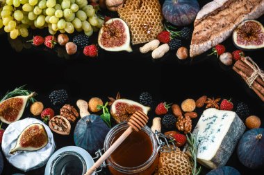 Siyah arka planda izole edilmiş bir şist tahtası üzerinde incir, böğürtlen ve ahududu içeren peynirli krem peyniri, düz bir zemin, kopyalama alanı.