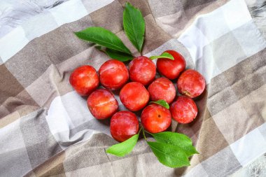 Eski ahşap arka planda kırmızı erikler, seçici odak.