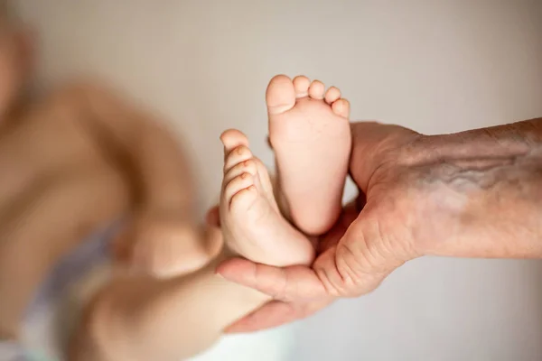 Handen Van Een Oude Vrouw Die Een Pasgeboren Baby Voeten — Stockfoto