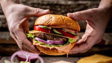 Ahşap masada şefin elleriyle lezzetli hamburgerler pişirmek. Yemek hazırlanıyor. menü.