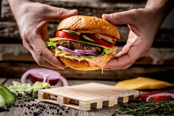 家庭を持つ手のクローズアップは 木製のヴィンテージテーブルの上においしいハンバーガーを作った — ストック写真