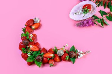 Pembe arka planda izole edilmiş taze çilek ve çikolata yığını. Yemek çerçevesi arka planı. Üst görünüm, metin için boş alan.