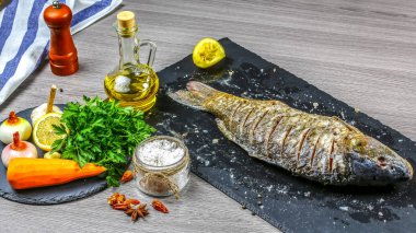 Şist tahtasında pişirmek için çeşitli malzemelerle büyük balık sazan balığı. Düz görünüm, metin menüsünü kopyala.