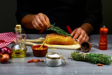 Aşçı elleri ahşap arka planda et, ot ve baharat pişiriyor. Yiyecek konsepti.