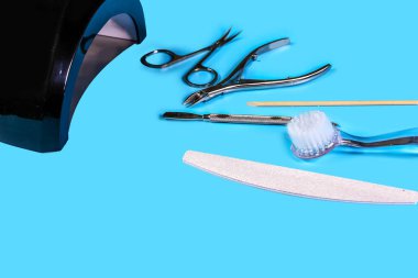 Manikür aleti ustanın elinde. Mavi arkaplan görünümlü pedikür aksesuarları. Kopya uzayı ile düz konum. Kişisel koruyucu ekipman kavramı.