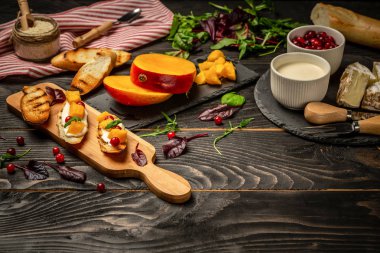 İtalyan aperatifi. Rostini, ricotta, mango, ahşap kaplama yaban mersini. Düz bir manzara. Boşluğu kopyala.