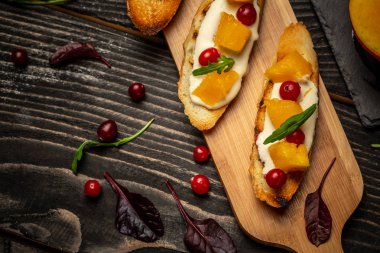 İtalyan yemeği pişirmek. Ricotta, mango, kızılcık ve peynirli peynirli crostini. Metni kopyala menü yiyecek arka planı.