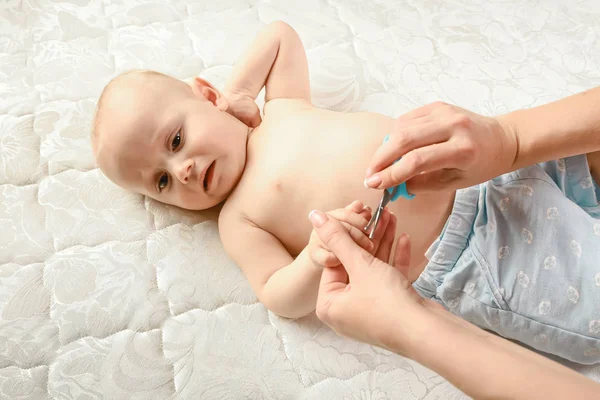 手で赤ちゃんのための爪と指マニキュアお母さんは愛とケアできれいに爪を切るために小さなはさみを保持しています — ストック写真