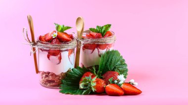 Taze çilekli tatlı, krem peynir ve bardakta çilek reçeli. Pembe arkaplanda izole edilmiş, kopyalama alanı.