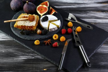 Peynirli Camembert peyniri. Bıçaklı, meyveli incirli ve böğürtlenli. Eski siyah ahşap masa. Şarap ve romantik yemekler, peynir şarküteri. Metin alanı.