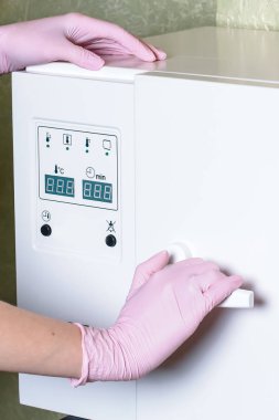 Çalışan manikür aletinin steril temizliği için ekipman. Süreç steril kıyafet manikür ustası bir hemşire tarafından gerçekleştiriliyor. dikey resim.