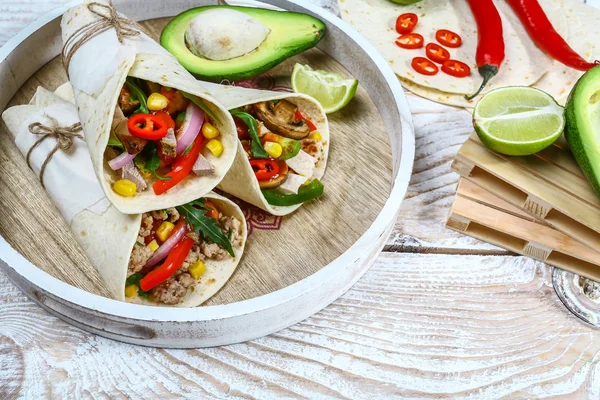 Meksika restoranı fast food. Domuz eti, mantar ve sebzelerle sarılmış burrito. Ahşap masada yakın plan. Meksika dürümleri yakın plan..