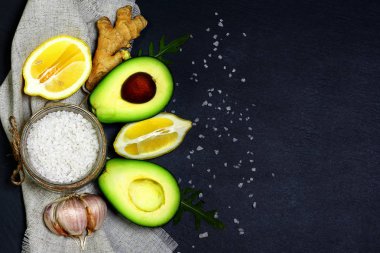 Yeşil sebzeler avokado, limon, zencefil, sarımsak, deniz tuzu, şist tahtasında roka salatası, sağlıklı beslenme konsepti, fotokopi alanı, üst görünüm seti.