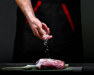 Şefin elleriyle tuz ekliyorum. Biftek fileto pişiriyorum. Basamaklar. Yiyecek konsepti.