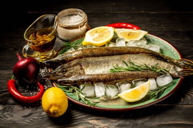 Çiğ çiğ mızrakları balık sebzeler, otlar ve baharatlar Doğrama Kurulu rustik ahşap arka plan üzerinde üstten görünüm üzerinde.