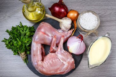 Çiğ tavşanla sebzeler ve ahşap arka planda taze otlar. Yukarıdan görüntüle.