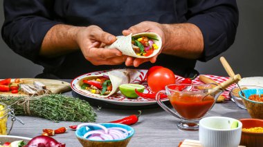 Meksika yemeği konsepti. Şef Meksika buritosu pişiriyor. Mutfakta enfes Meksika Burito 'su hazırlıyorum..