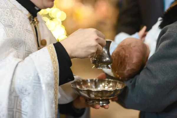 Bautismo infantil. Ceremonia de bautismo en la Iglesia. El agua se vierte en la cabeza de un bebé —  Fotos de Stock