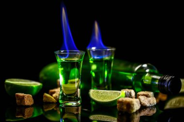 pelin koyu arka plan üzerine kireç dilimleri ile cam. Şişe absinthe ve burning ile bardak. küp esmer şeker. metin için özgür yer. elit alkol kavramı