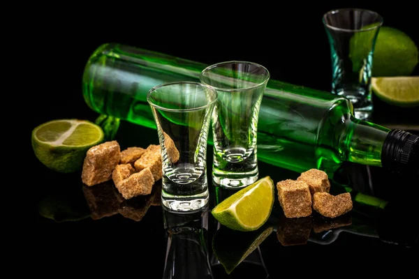 Liqueur italienne ou tchèque traditionnelle ou amère aux tranches de lime. Trois verre absinthe, cube de sucre brun sur fond sombre. espace libre pour le texte. le concept d'alcool d'élite — Photo