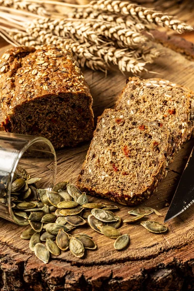 Pão de grão inteiro com sementes de baga de goji, abóbora, em uma chapa em um contexto de madeira, comida rural. vista superior — Fotografia de Stock