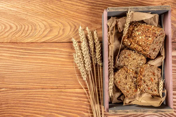 Pane integrale con semi di bacca di goji, con punte di grano su uno sfondo di legno, cibo rurale. vista dall'alto — Foto Stock