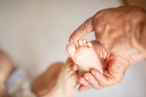 Overgrootmoeder die kleine babyvoet aanraakt, het concept van een gezin en een nieuw leven. in een selectieve focus — Stockfoto