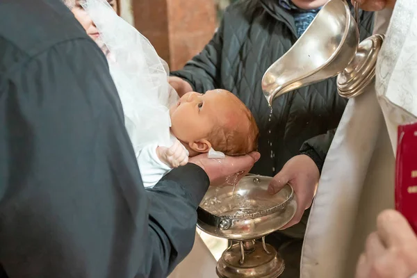 Keresztelő szertartás a templomban. szentelt vizet öntsön a fejére egy fehér takaróra, keresztelje meg a babát az ortodox templomban. — Stock Fotó