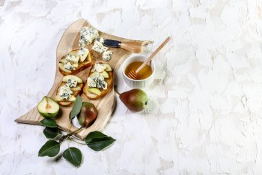 Ahşap kesim tahtasında armut, bal ve mavi peynirli tost veya bruschetta. Nefis bir kahvaltı ya da hafif bir arka planda atıştırmalık.