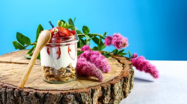 Çilekli, cam kavanozda, mavi arka planda krem peynirli, ferahlatıcı tatlı. Uzayı kopyala Sağlıklı ev yapımı tatlı.