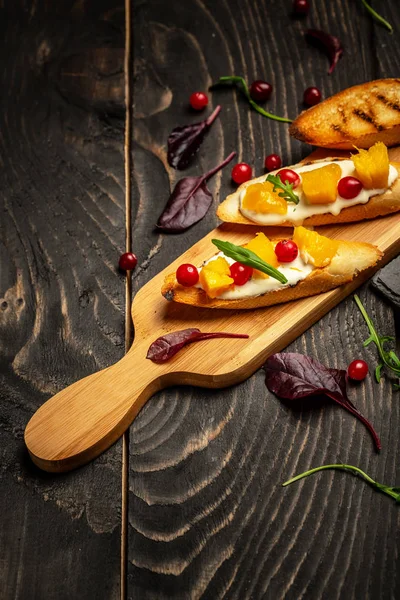 Bruschetta dengan mangga manis, delima, keju. pada latar belakang kayu. Makanan sehat, tampilan atas rata — Stok Foto