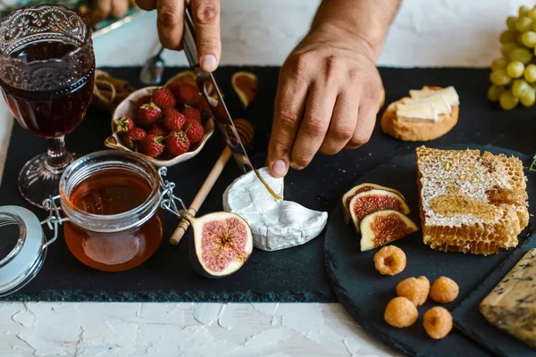 Formaggio Camembert con fichi e noci in mano in cucina. sul tagliere in legno. Vista da vicino, Ingredienti per una colazione sana — Foto Stock