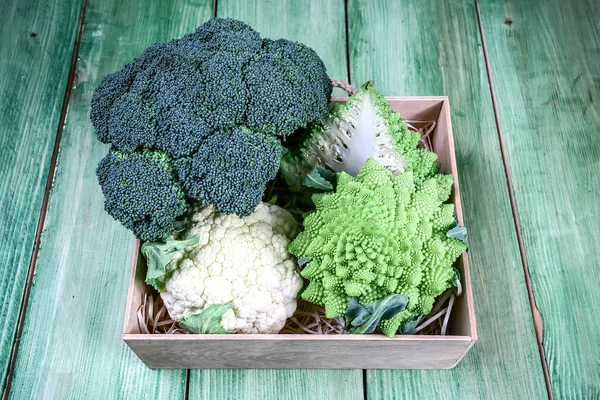 Samling av Romanesco broccoli och blomkål i en trälåda på köksbordet — Stockfoto