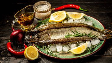 Karanlık vintage zemin üzerine lezzetli taze balık. Aromatik otlar, baharatlar ve sebzeler - sağlıklı gıda, diyet veya pişirme kavramı ile balık. Üstten Görünüm