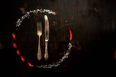 Çember çerçeve kompozisyonu kırmızı biber ve baharatlar, siyah arka planda çatal ve bıçak. Hint baharatları ve otlarından oluşan bir çerçeve. Asya mutfağı baharatlarının içeriği. Kopyalama alanı ile hava görünümü