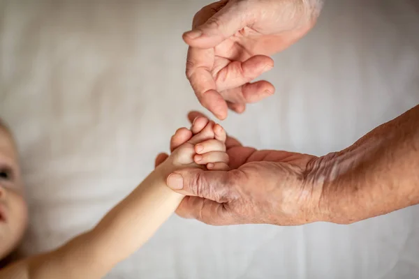Oude en pasgeboren handen aanraken elkaar. handen close-up. Moeder en haar kind. Gelukkig familieconcept. Mooi conceptueel beeld van moederschap — Stockfoto