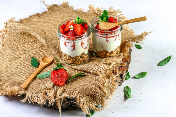 layered dessert with strawberries, biscuit cake and cream cheese on wood background. Copy space