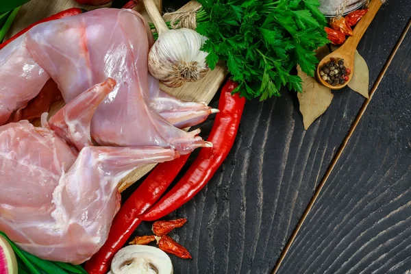 Raw rabbit meat with herbs and spices on a wooden background. top view and blank place