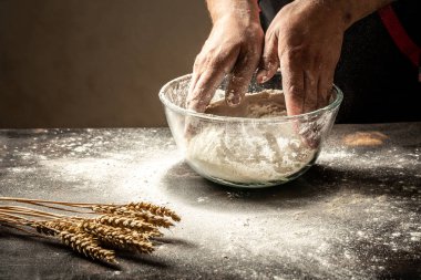 Erkekler elleri yakından un ile bir hamur serpin. Ekmek hamuru hazırlayan adam. Gıda konsepti