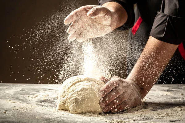 Chef händer matlagning deg på mörkt trä bakgrund. Vitt mjöl som flyger upp i luften. Livsmedelsidé — Stockfoto