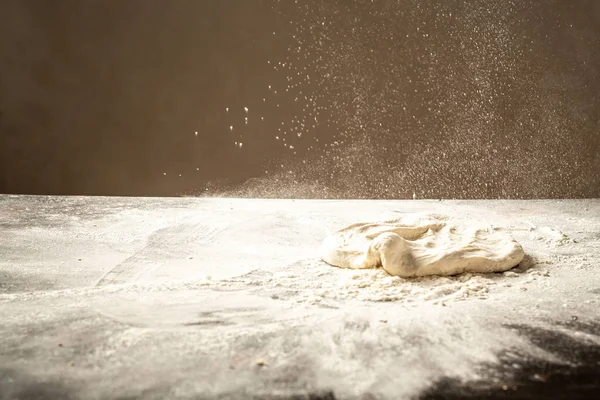 Palla di pasta per pizza su fondo rustico in legno con spolverata di farina che vola nell'aria. Concetto alimentare — Foto Stock