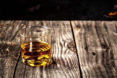 Erkeksi rahatlama için elit içecek. ahşap plakalar üzerinde servis edilen viski. Vurgulamak ve sert likör bir bardak ile Vintage tezgah. Metniniz için boş alan