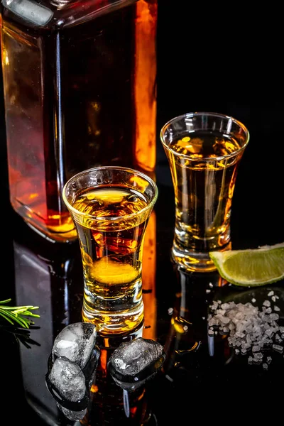 Tequila de oro con rodaja de lima sobre fondo negro, espacio para copiar. concepto bebida de lujo — Foto de Stock