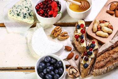 Taze çilek yaban mersini ve peynir, kekik ve fındık, beyaz ahşap dokulu tahta üzerinde tost crostini. Üst görünüm, kopyalama alanı