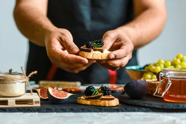 Conceito de receita alimentar. Torradas de queijo, figos e mel nas mãos na cozinha. Este Fig. e Gorgonzola tartines, torradas, bruschetta. chuviscada com mel — Fotografia de Stock