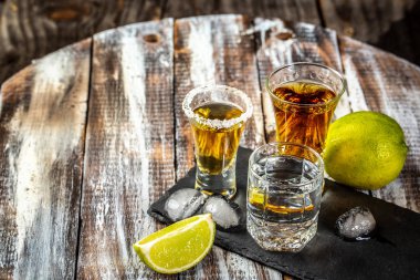 Bardakta farklı alkollü içki. Rustik ahşap arka plan üzerinde kireç ve tuz ile Meksika tekila. metin için alan. konsept lüks içecek