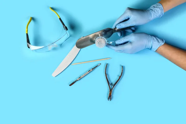 Manicure tool in the hands of the master. set of manicure and pedicure accessories on blue background top view. flat lay composition with copy space. the concept of personal protective equipment