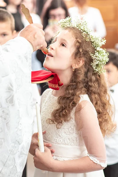Erstkommunion. Porträt des süßen kleinen Mädchens auf weißem Kleid und Kranz zur Erstkommunion — Stockfoto